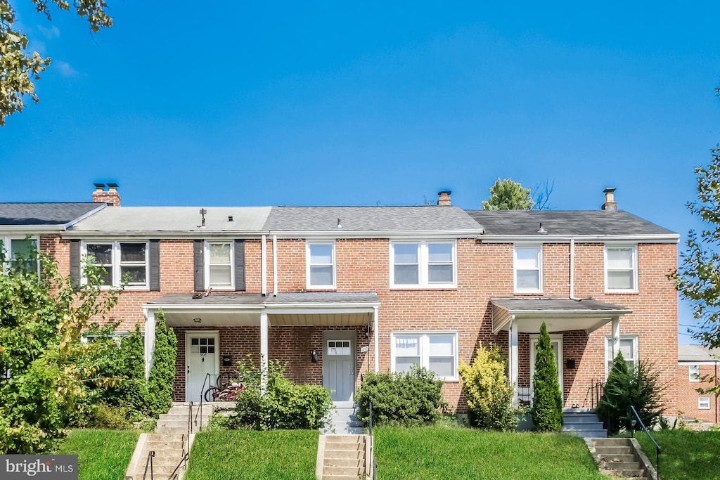 multi unit property featuring a front yard and covered porch