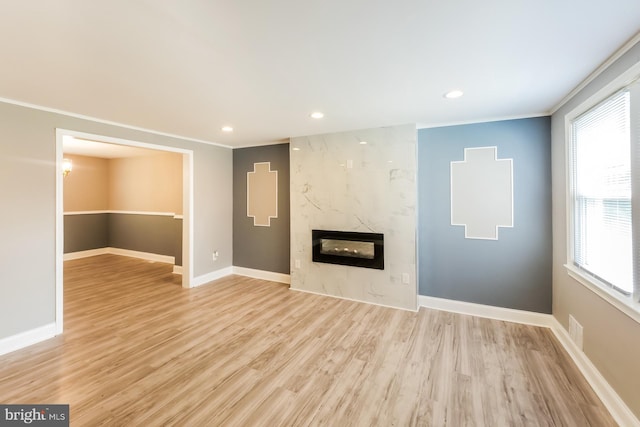 unfurnished living room featuring light hardwood / wood-style floors, ornamental molding, and a high end fireplace