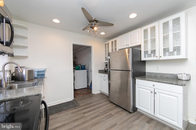 kitchen featuring electric range, white cabinets, washer / clothes dryer, freestanding refrigerator, and a sink