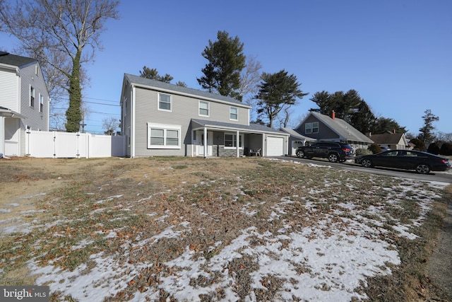 traditional-style home featuring driveway, an attached garage, covered porch, a gate, and fence