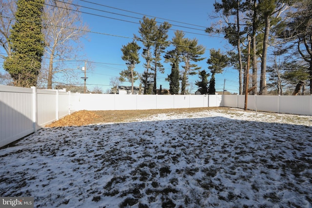 yard layered in snow with a fenced backyard