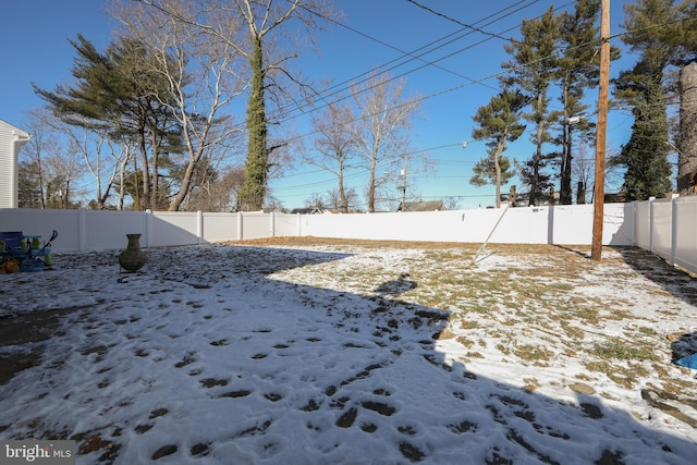 yard covered in snow with a fenced backyard