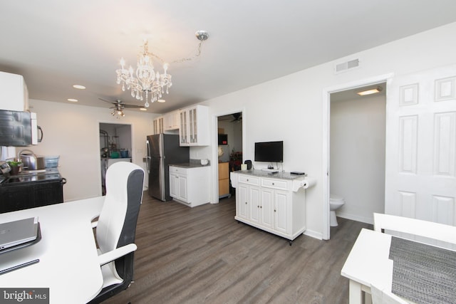 office featuring ceiling fan with notable chandelier, dark wood-style flooring, visible vents, and baseboards