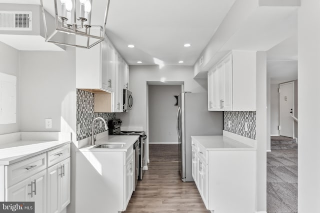 kitchen with tasteful backsplash, white cabinetry, sink, and appliances with stainless steel finishes