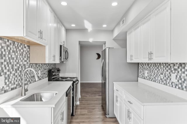 kitchen featuring backsplash, white cabinetry, sink, and appliances with stainless steel finishes