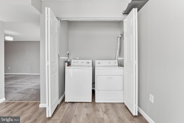 clothes washing area with washer and clothes dryer and light hardwood / wood-style flooring