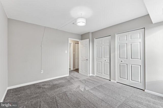 unfurnished bedroom with two closets and light colored carpet