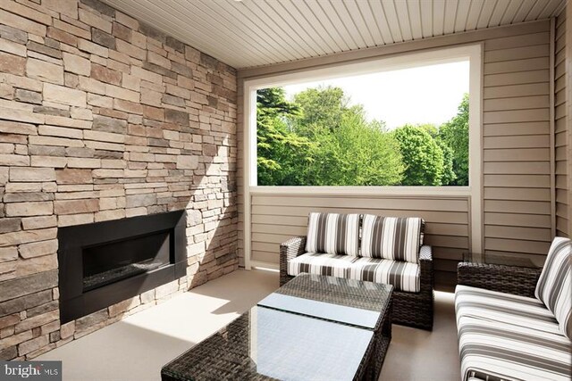 sunroom with wood ceiling, a healthy amount of sunlight, and an outdoor stone fireplace