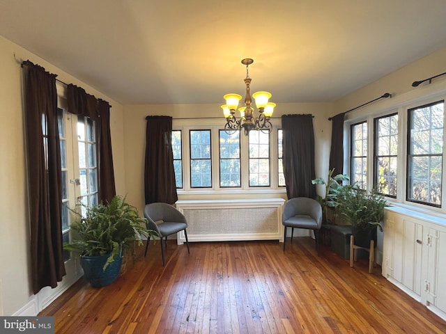 unfurnished room featuring radiator, a chandelier, and wood-type flooring