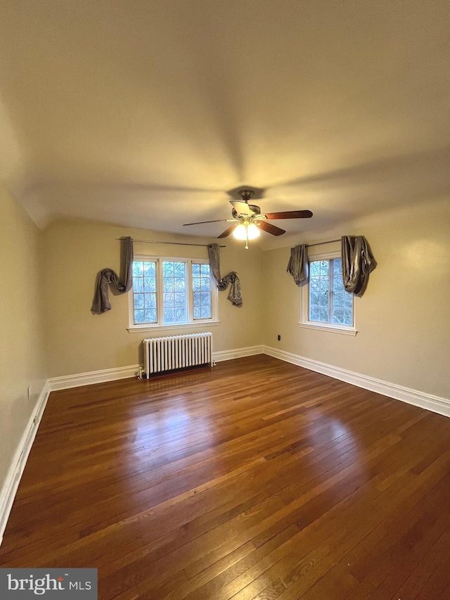 unfurnished room with radiator, ceiling fan, dark hardwood / wood-style flooring, and a healthy amount of sunlight