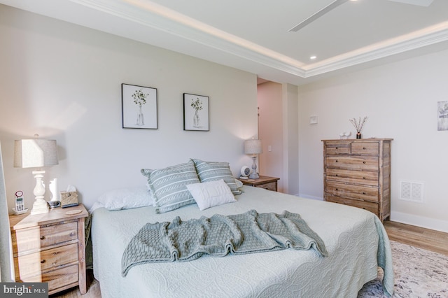 bedroom with hardwood / wood-style flooring, ceiling fan, and a tray ceiling