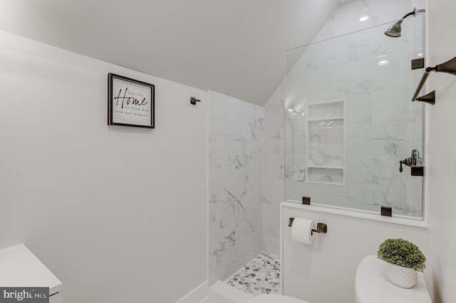 bathroom with vaulted ceiling and tiled shower