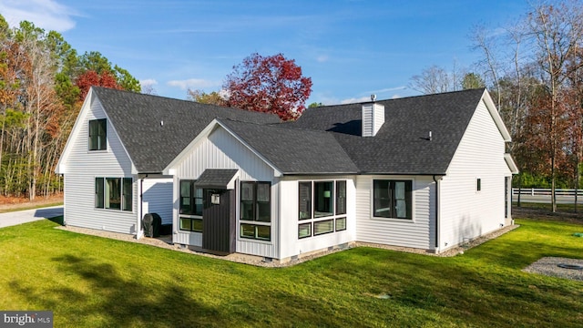 rear view of house with a lawn and a sunroom