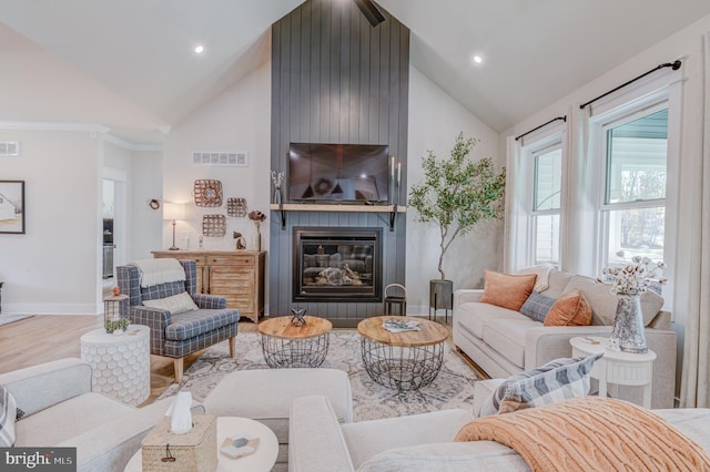 living room featuring hardwood / wood-style floors, a large fireplace, and high vaulted ceiling