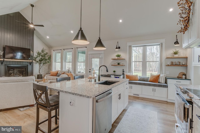 kitchen with white cabinets, appliances with stainless steel finishes, a center island with sink, and sink