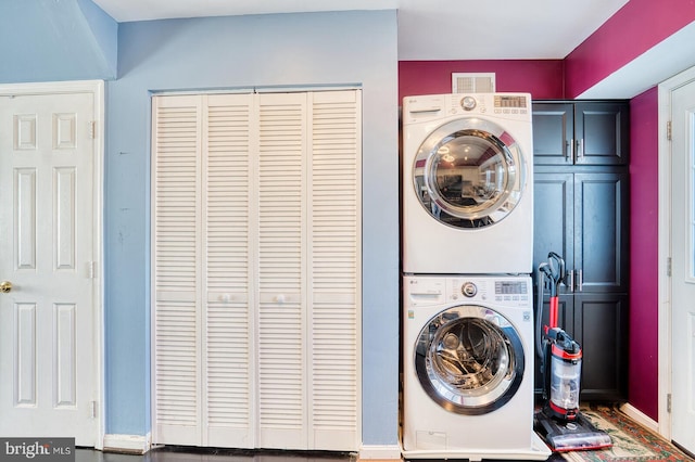 laundry area with cabinets and stacked washer / drying machine