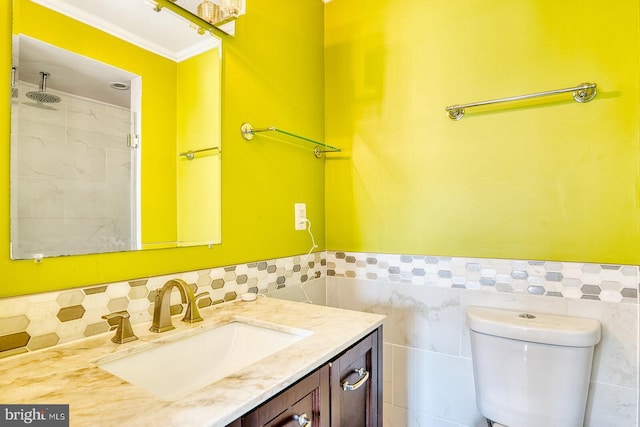 bathroom with vanity, toilet, ornamental molding, and tile walls