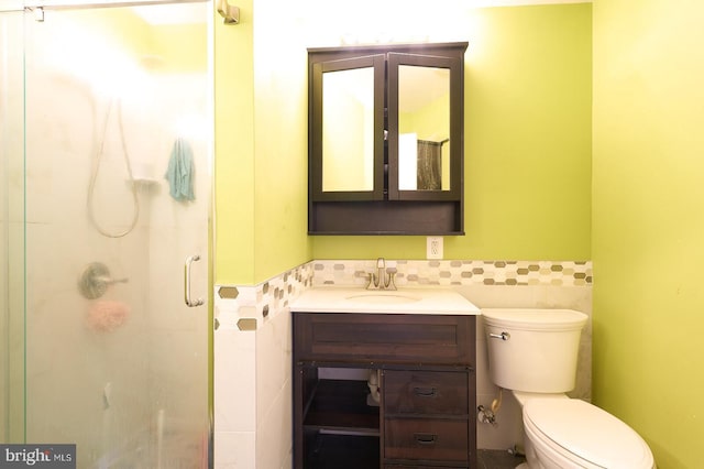 bathroom featuring vanity, toilet, tile walls, and walk in shower