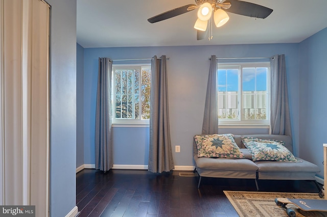 living area with a wealth of natural light, dark hardwood / wood-style flooring, and ceiling fan