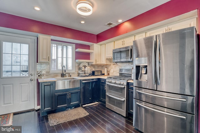 kitchen with backsplash, blue cabinets, sink, appliances with stainless steel finishes, and dark hardwood / wood-style flooring