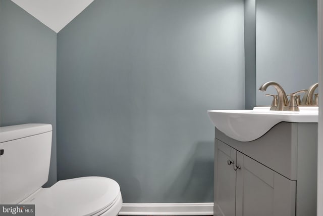 bathroom with vanity, vaulted ceiling, and toilet