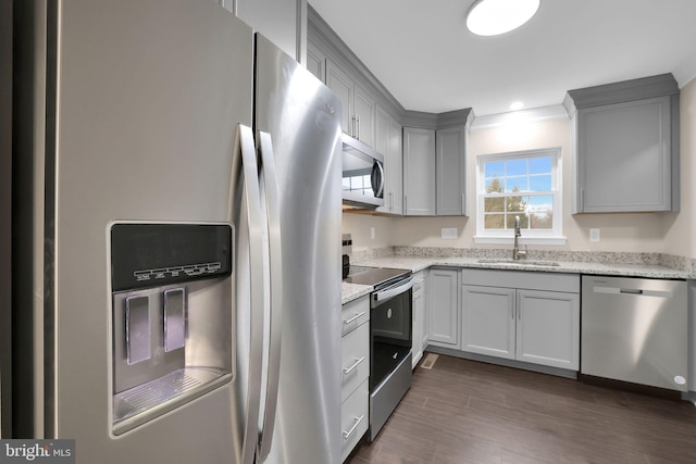 kitchen featuring stainless steel appliances, light stone counters, dark wood-type flooring, and sink