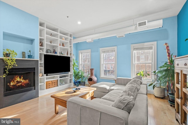 living room featuring light wood-type flooring and built in features