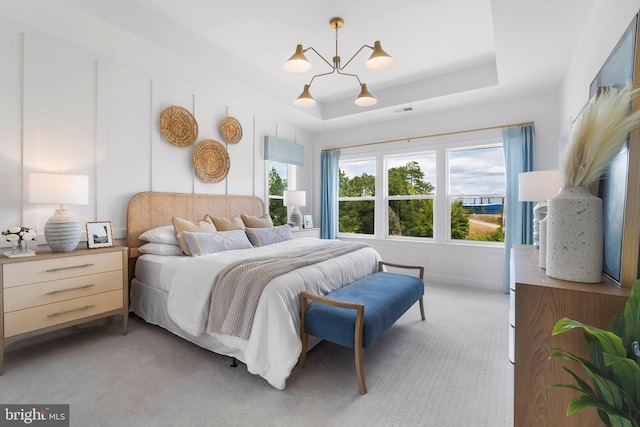 bedroom featuring a tray ceiling, light carpet, and a notable chandelier