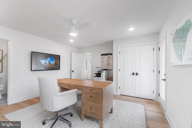 home office with light wood-type flooring and ceiling fan