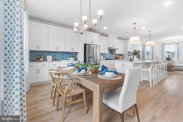 dining space featuring light wood-type flooring and an inviting chandelier