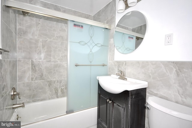 full bathroom featuring vanity, toilet, bath / shower combo with glass door, and tile walls