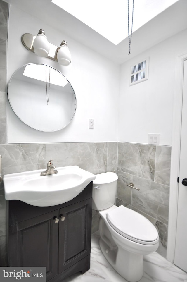 bathroom with vanity, tile walls, and toilet