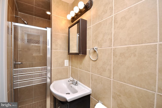 bathroom featuring vanity, tile walls, and a shower with shower door