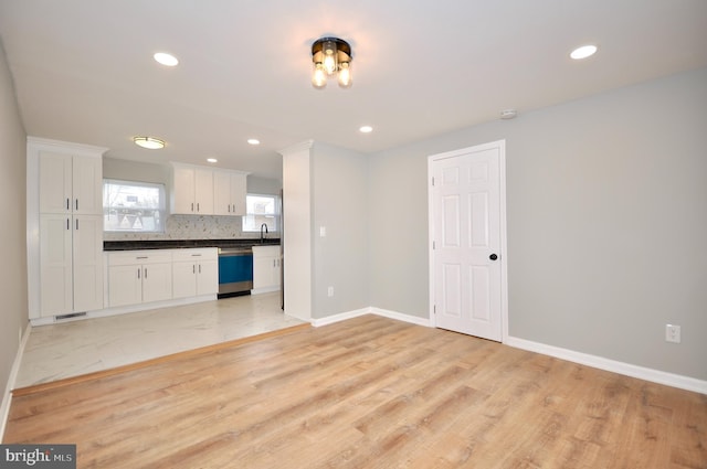 kitchen with white cabinetry, sink, stainless steel dishwasher, and light hardwood / wood-style floors