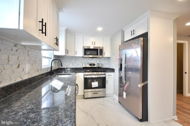 kitchen with sink, dark stone countertops, decorative backsplash, white cabinets, and appliances with stainless steel finishes