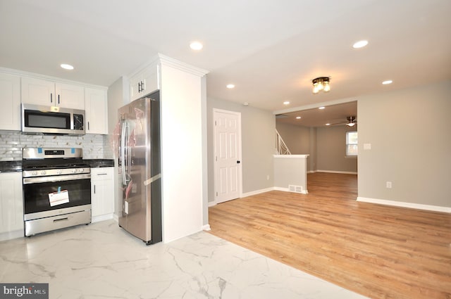 kitchen featuring decorative backsplash, appliances with stainless steel finishes, ceiling fan, light hardwood / wood-style floors, and white cabinetry