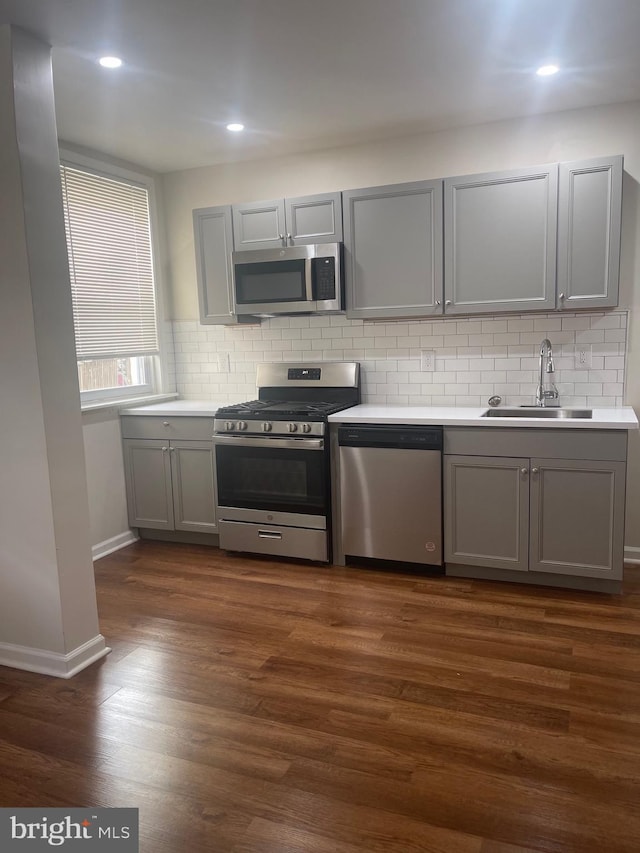 kitchen featuring gray cabinetry, sink, stainless steel appliances, and dark wood-type flooring