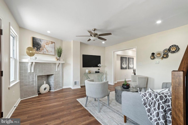 living room featuring ceiling fan, dark hardwood / wood-style flooring, and a fireplace