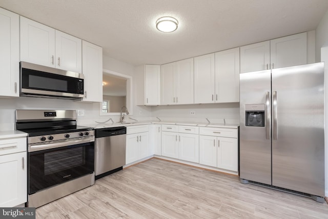 kitchen with white cabinets, stainless steel appliances, and light hardwood / wood-style floors