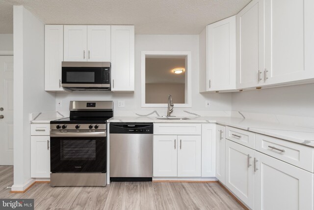 117 N Virginia Ave, Richmond, VA 23223 - kitchen with stainless steel appliances, a sink, white cabinetry, light wood-style flooring, and light stone counters