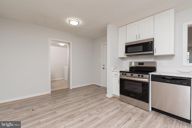 kitchen featuring a textured ceiling, light wood-type flooring, white cabinetry, and stainless steel appliances