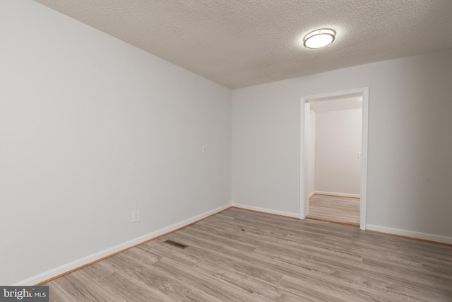 unfurnished room with light wood-type flooring and a textured ceiling