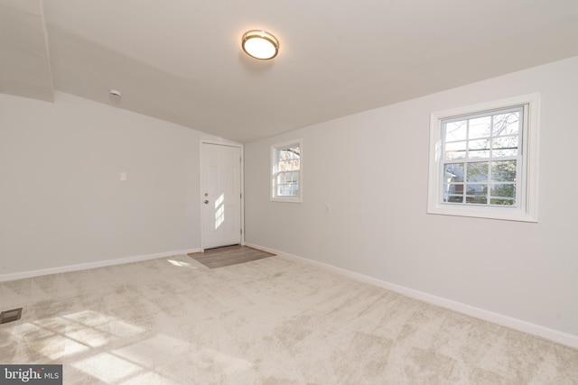 carpeted empty room with vaulted ceiling