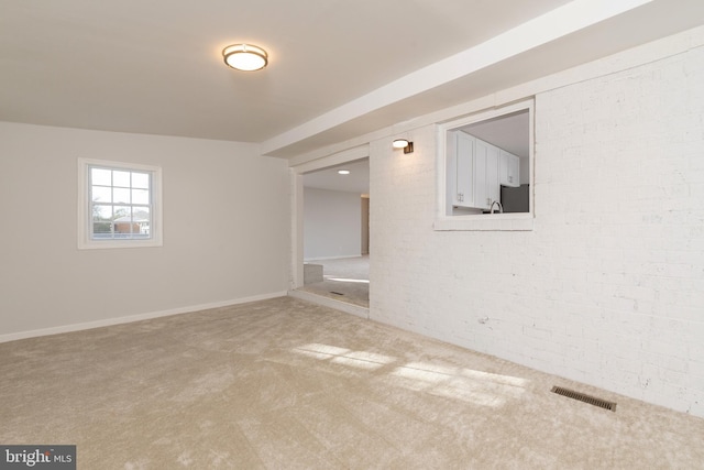 spare room featuring carpet floors and brick wall