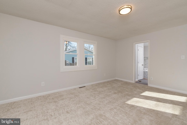 spare room featuring a textured ceiling and light colored carpet