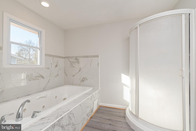 bathroom with wood-type flooring and tiled tub