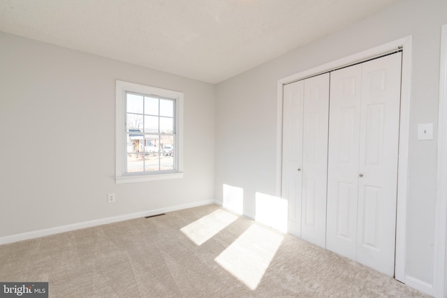 unfurnished bedroom with light carpet and a closet