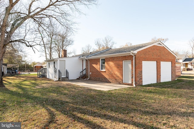 back of property with a yard, a garage, and a patio area