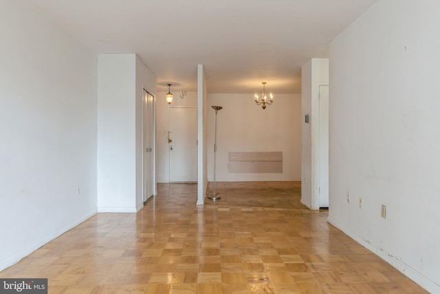 empty room with light parquet flooring and an inviting chandelier