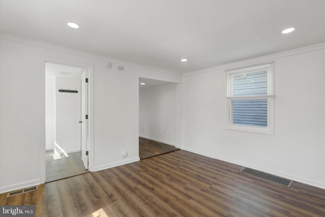 spare room with crown molding and dark wood-type flooring